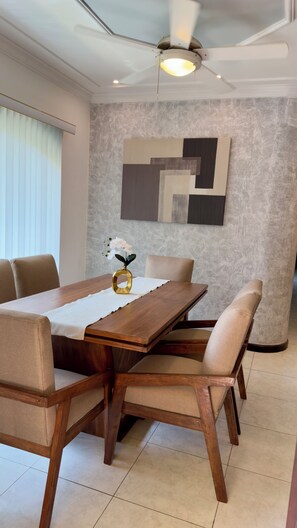 A dining area with a wooden table, beige upholstered chairs, a ceiling fan, and a textured wall. - Spacious 3-bedroom apartment with a pool in Boca del Río (boca del rio)