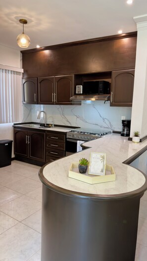 A modern kitchen with dark cabinetry, a stainless steel range, and a marble countertop. - Spacious 3-bedroom apartment with a pool in Boca del Río (boca del rio)