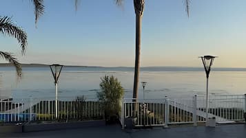 A waterfront property with a gated entrance, palm trees, and a clear view of the water.