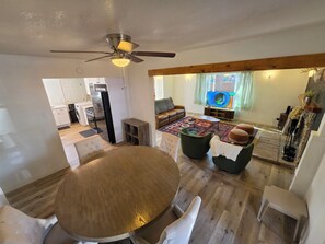 A modern living space with a dining area, a kitchen, and a seating area with a television. - Cozy Big Bear Cabin _Game Room-Pet Friendly- Near Lake-Sleeps 8 (Big Bear)