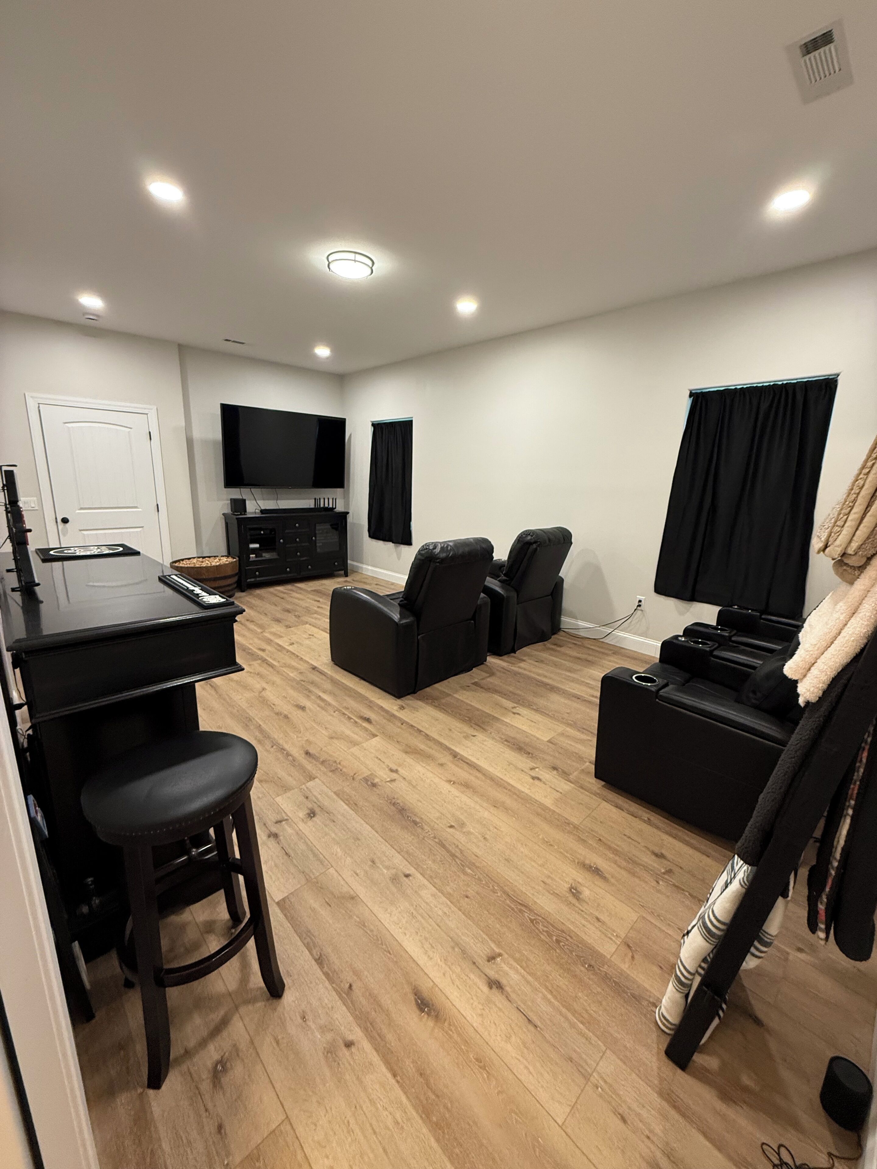 A modern living room with a flat-screen TV, a gaming console, and a sofa.