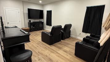 A modern living room with a flat-screen TV, a gaming console, and a sofa.