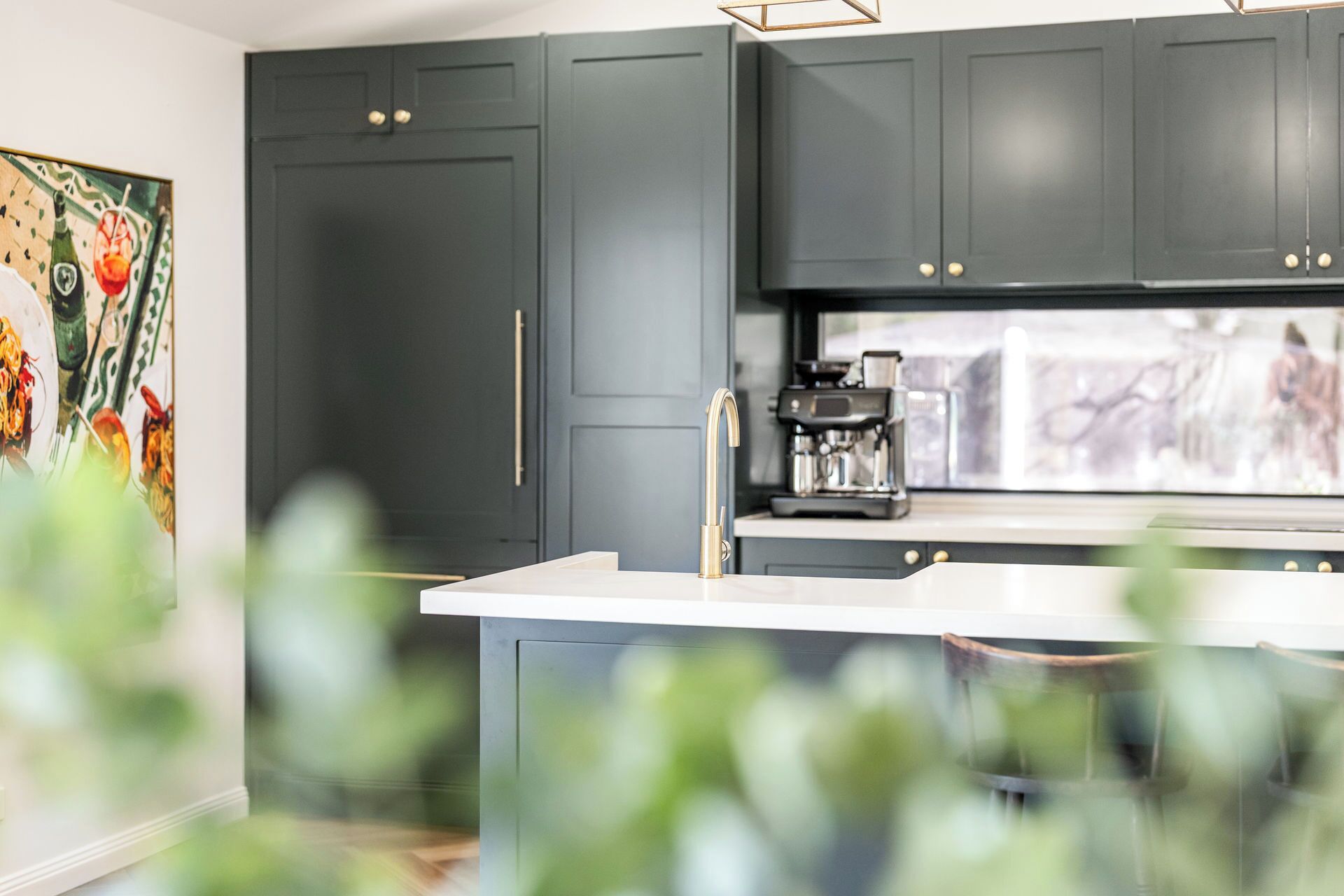 A modern kitchen with dark cabinets, a coffee machine, and a large window.