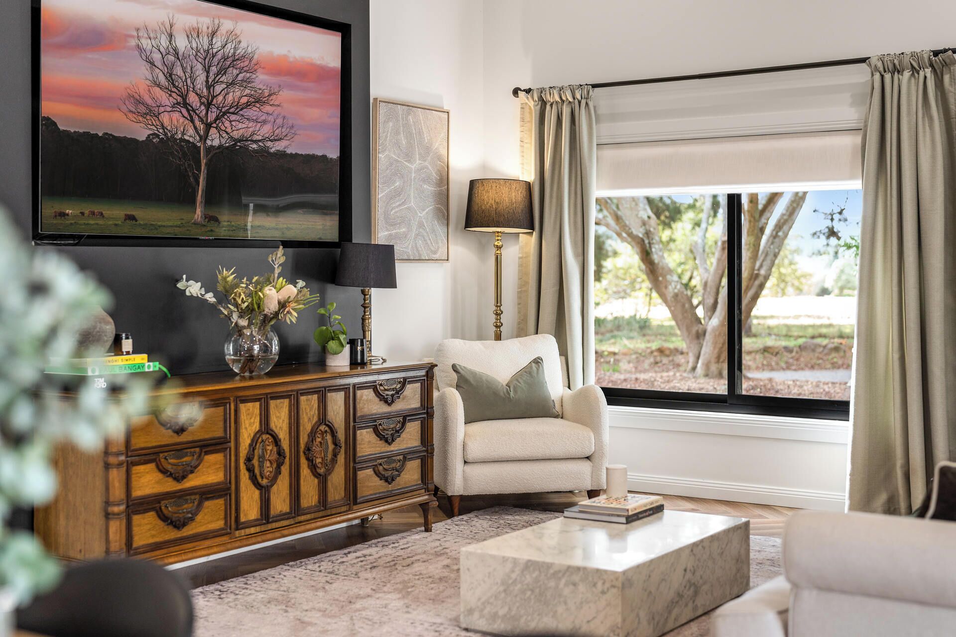 A living room with a television, a sofa, a coffee table, a cabinet, and a window with curtains.
