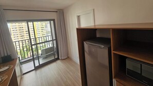 A modern apartment with a balcony, a refrigerator, and a TV stand. - Apartamento com varanda - Pinheiros (São Paulo)