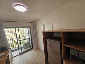 A modern apartment with a balcony, a refrigerator, and a TV stand. - Apartamento com varanda - Pinheiros (São Paulo)
