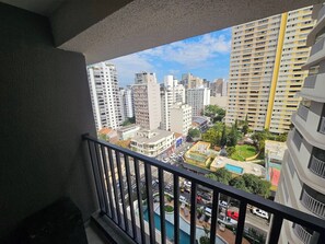 Un balcón con vista a un paisaje urbano, que incluye rascacielos y una piscina.
