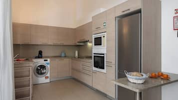 Una cocina moderna con refrigerador de acero inoxidable, horno empotrado, microondas y lavadora.