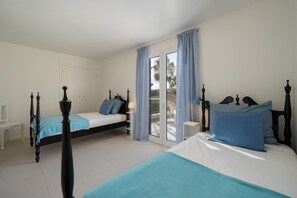 Un dormitorio con dos camas, una puerta blanca y vistas al exterior.