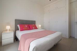 Et soveværelse med seng, sengeborde, et skab og en loftlampe.