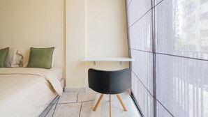 A bedroom with a bed, pillows, a bedside table, and a chair. - Palmier • 1BR avec balcon & parking (Casablanca)