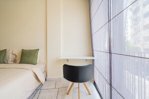 A bedroom with a bed, pillows, a bedside table, and a chair. - Palmier • 1BR avec balcon & parking (Casablanca)
