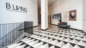 A modern interior with a geometric patterned floor, a staircase with metal railings, and a wall with the text 'B L I V I N G'. - Palmier • 1BR avec balcon & parking (Casablanca)
