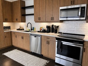 A modern kitchen with wooden cabinets, stainless steel appliances, a dishwasher, and a microwave. - 2bed/2bath Midtown-Atlanta
Secure Parking
Walking Distance to Retail Shops (Atlanta)