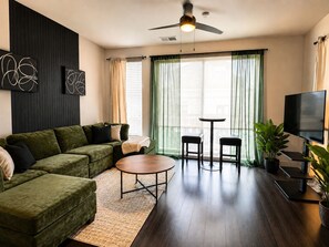 A living room with a green sofa, a round coffee table, a TV, and a ceiling fan. - 2bed/2bath Midtown-Atlanta
Secure Parking
Walking Distance to Retail Shops (Atlanta)