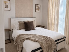 A bed with a white mattress, two pillows, a beige throw blanket, and a headboard. There are two bedside tables with lamps, a window with blinds, and artwork on the walls. - 2bed/2bath Midtown-Atlanta
Secure Parking
Walking Distance to Retail Shops (Atlanta)