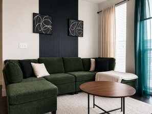 A modern living room with a green sectional sofa, a round wooden coffee table, and abstract wall art. - 2bed/2bath Midtown-Atlanta
Secure Parking
Walking Distance to Retail Shops (Atlanta)