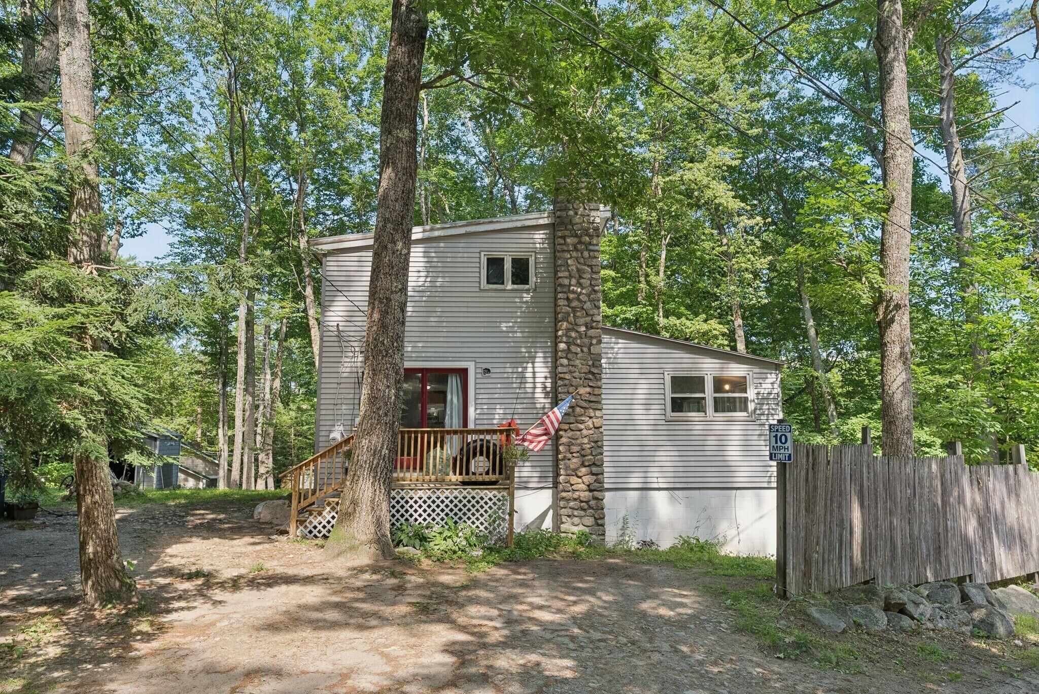 A cabin with a porch, surrounded by trees.