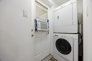 Ett tvättrum med en tvättmaskin och en torktumlare som båda har frontmatning, en dörr med handtag och en ventilationshuv över torktumlaren.