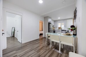 Eine moderne Küche mit weißen Schränken, einem Glastisch und einem Kühlschrank.
