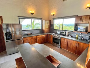 A modern kitchen with a large island, stainless steel appliances, and wooden cabinets. - Sunset Villa Macaw, 2 King Suites, Pool & Ocean View (Manuel Antonio)