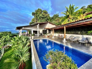 A modern poolside area with a clear blue pool, lounge chairs, and a covered patio. - Sunset Villa Macaw, 2 King Suites, Pool & Ocean View (Manuel Antonio)