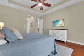 A bedroom with a bed, a dresser, a painting, and a ceiling fan. - Private Pool Villa | Players Club & Spa | Golf Views (Naples)