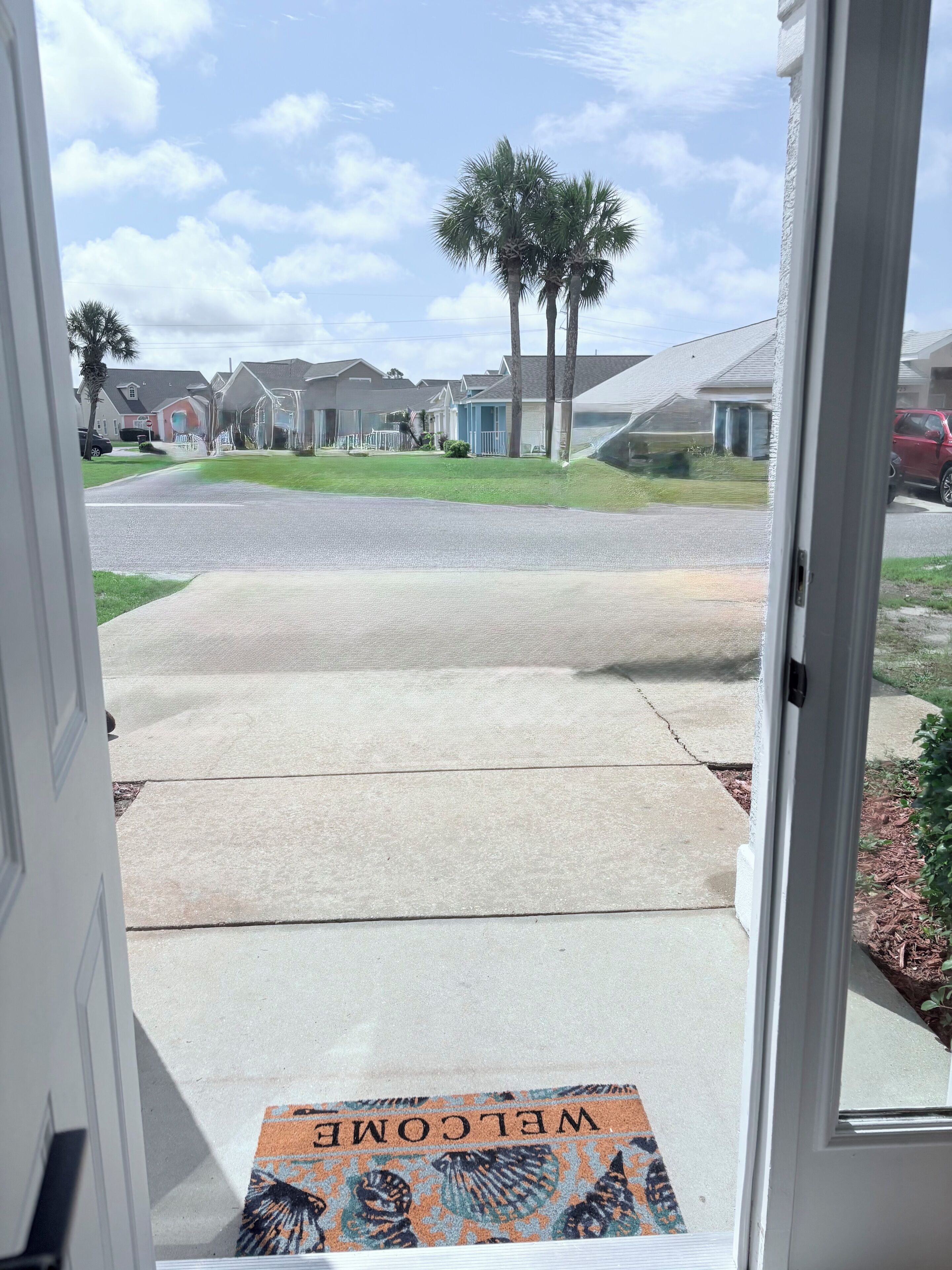 A residential driveway leading to a house with a welcome mat.