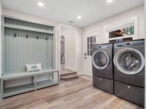 A laundry room with a bench and two front-loading washing machines. - Gabriel Getaway | Mountain Comfort in Skyland, NV (Zephyr Cove)