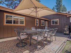 A patio with a table and chairs, a grill, and a large umbrella. - Gabriel Getaway | Mountain Comfort in Skyland, NV (Zephyr Cove)