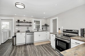 Una cocina moderna con armarios blancos, estufa de acero inoxidable y horno empotrado.