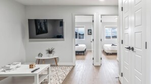 A modern bedroom with a bed, a TV, and a small table with books and a plant. - Luxurious  4-bedroom house w/ Free Banff Pass (Northeast)