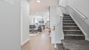 A modern interior with a staircase, a living area with a sofa and coffee table, and a kitchen in the background. - Luxurious  4-bedroom house w/ Free Banff Pass (Northeast)