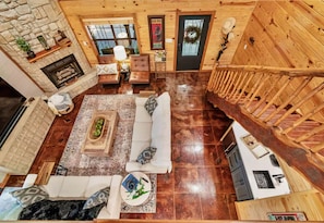 A spacious living area with a fireplace, a sofa set, a dining table, and a staircase leading to an upper level. - Heated Pool | Boat Parking | Outdoor Kitchen (Broken Bow)