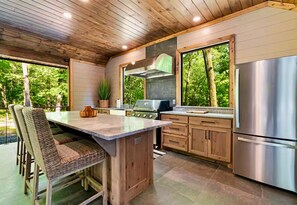 A modern kitchen with a central island, stainless steel appliances, and large windows. - Heated Pool | Boat Parking | Outdoor Kitchen (Broken Bow)