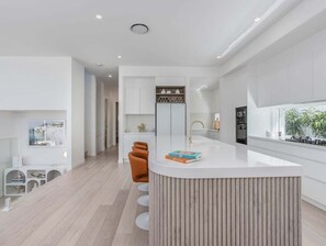 Een moderne keuken met een centraal eiland, witte kasten en uitzicht op de omgeving.