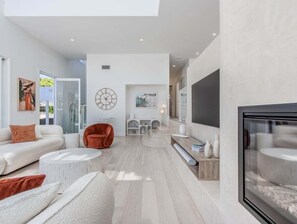 A modern living room with a sofa, armchair, and a fireplace. - 23 Lancelin Drive Mermaid Waters (Gold Coast)