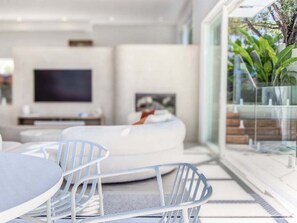 A modern living room with a sofa, a TV, and a glass table. - 23 Lancelin Drive Mermaid Waters (Gold Coast)