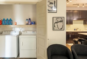 A laundry area with two washing machines, a drying rack, and various cleaning supplies. - Skyline-View, 2BR, 2.5Bt, Pool, Gym& Free Parking (Dallas)