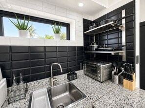 Una cocina moderna con salpicadero blanco y negro, un lavamanos de acero inoxidable y un horno empotrado.