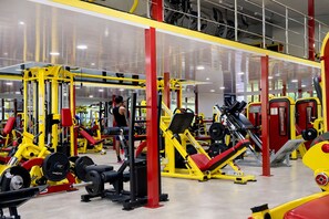 Un gimnasio con varios equipos de ejercicio, incluyendo máquinas de pesas y pesas libres.