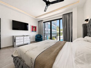 Un dormitorio moderno con una cama grande, un televisor de pantalla plana, un aparador y un ventanal con vistas a edificios.