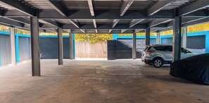 A covered parking area with concrete floors and metal beams. - Cozy 1-bedroom apartment in tranquil Sosúa with AC, Hot Water, Pool and GYM (Sosúa)