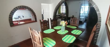 A dining area with a wooden table, chairs, and a vase with flowers.