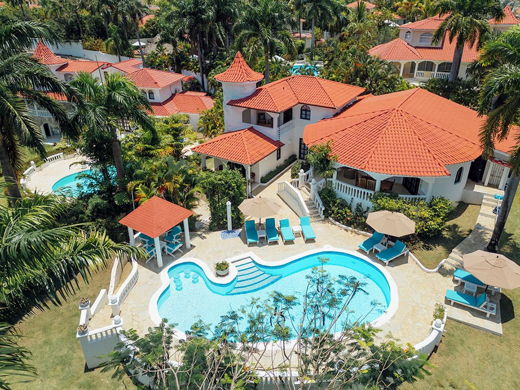 A resort with multiple buildings, a swimming pool, and lounge areas.