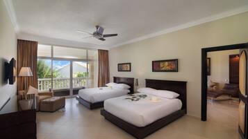 A hotel room with two beds, a ceiling fan, a balcony with curtains, and a view of the outdoors.