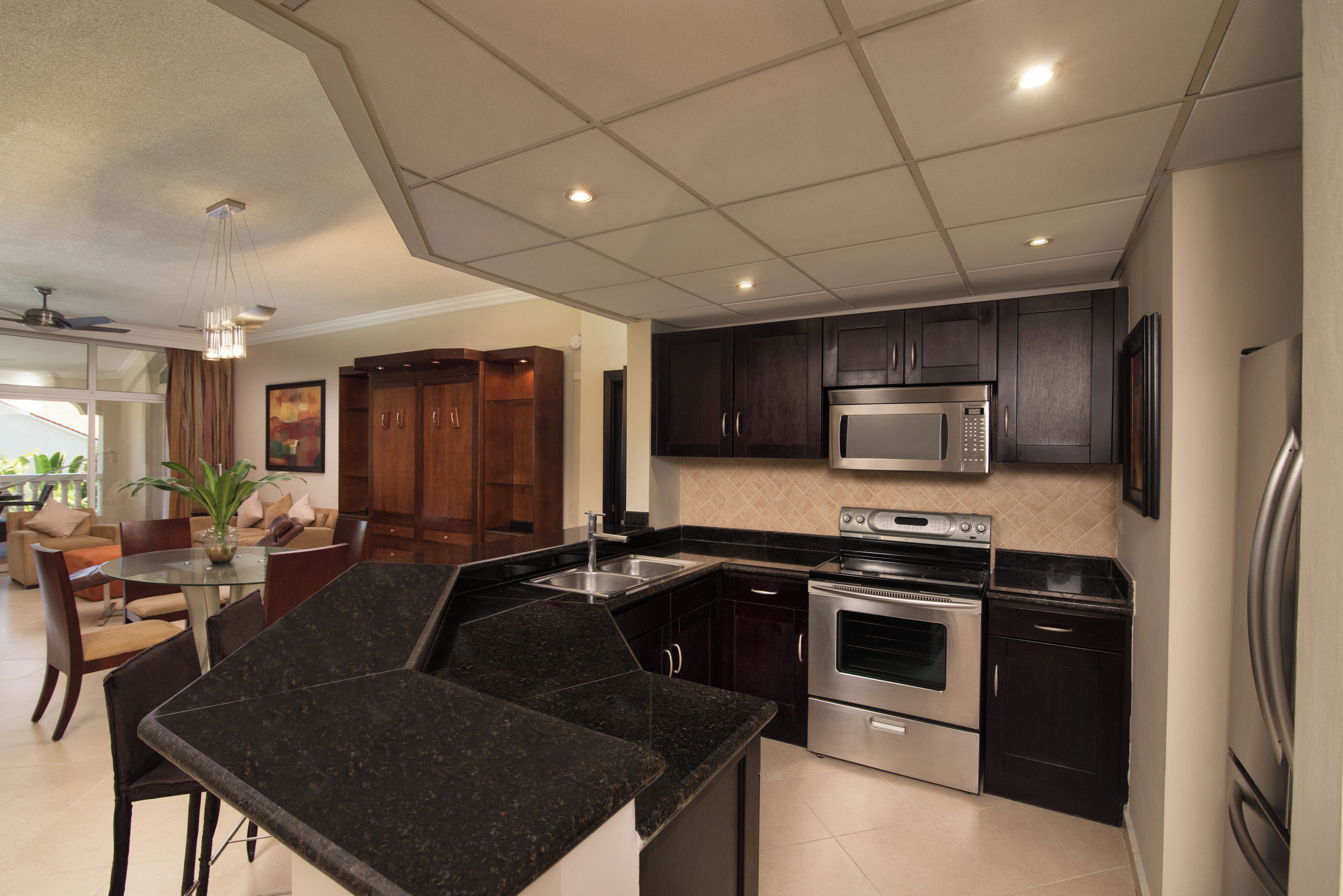 A modern kitchen with dark cabinets, stainless steel appliances, and a glass dining table.