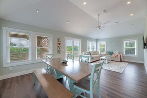A spacious living area with a dining table, chairs, a sofa, and a ceiling fan.