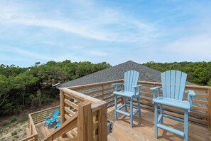 Eine Holzterrasse mit zwei blauen Adirondack-Stühlen und einem Hollerdungszaun.