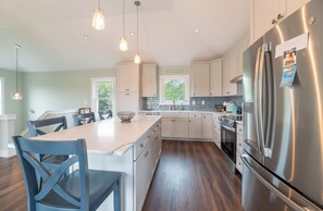 A modern kitchen with stainless steel appliances, a central island, and pendant lighting.